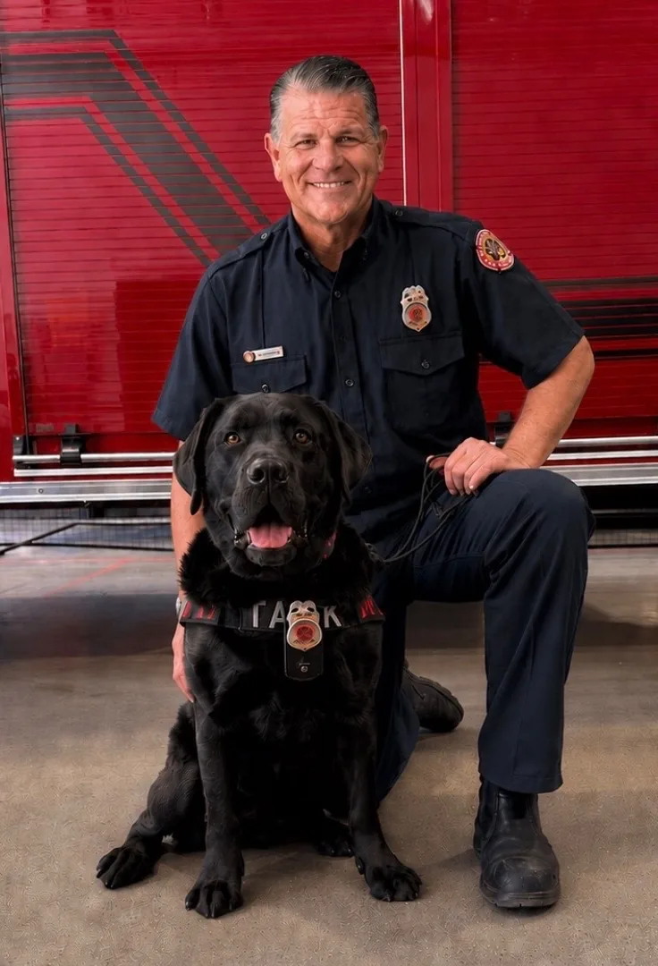 Matt Terry and Tank, Terry Fire Investigations' certified Ignitable Liquid Detection K9 team, in front of a fire engine